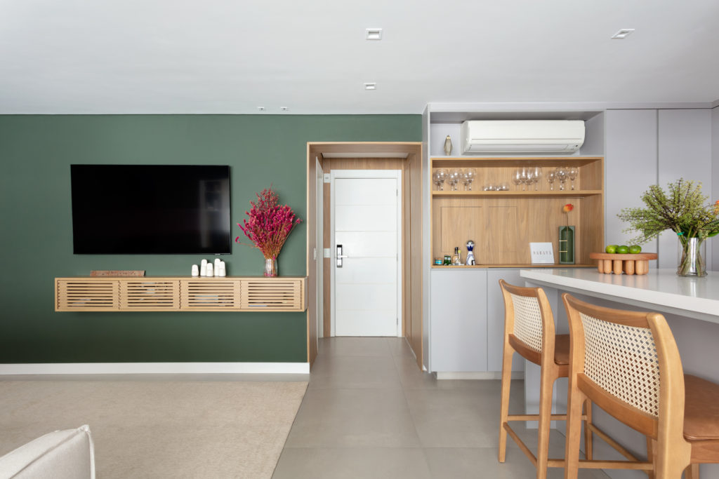 Sala de estar com parede verde musgo, painel ripado e adega — reforma completa Obrafy no Brooklin