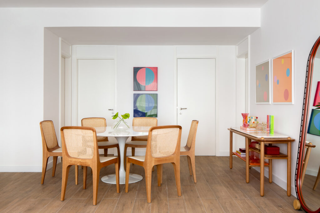 Sala de jantar com cadeiras de vime, mesa Saarinen e obras de arte — projeto de interiores Obrafy no Itaim Bibi
